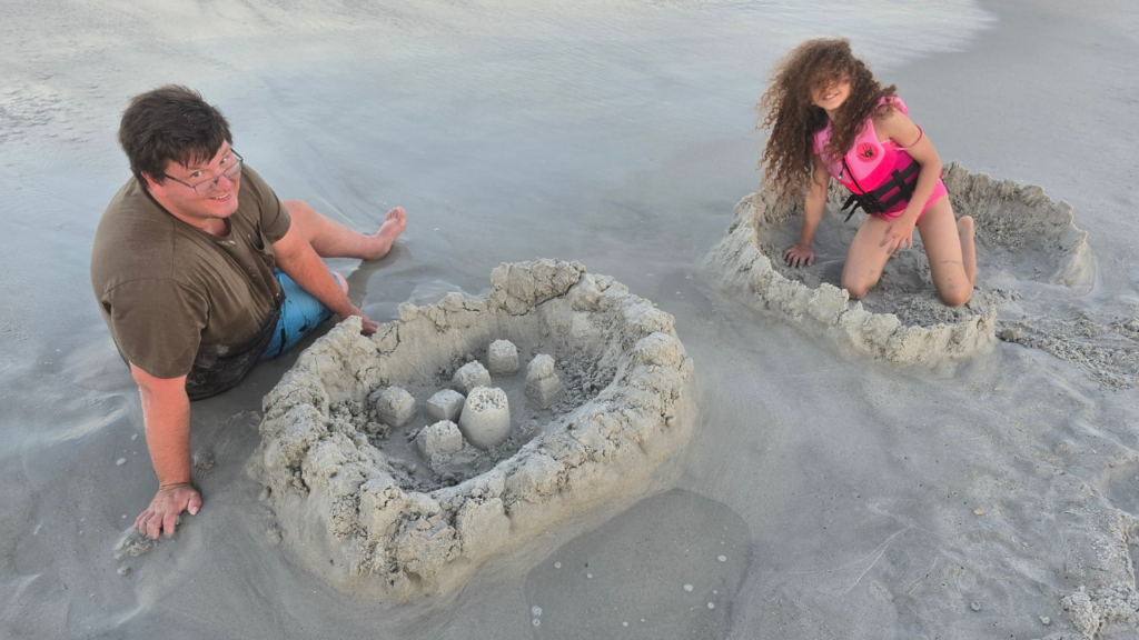 Caucasian dad and biracial daughter building sandcastles in the sand at the beach