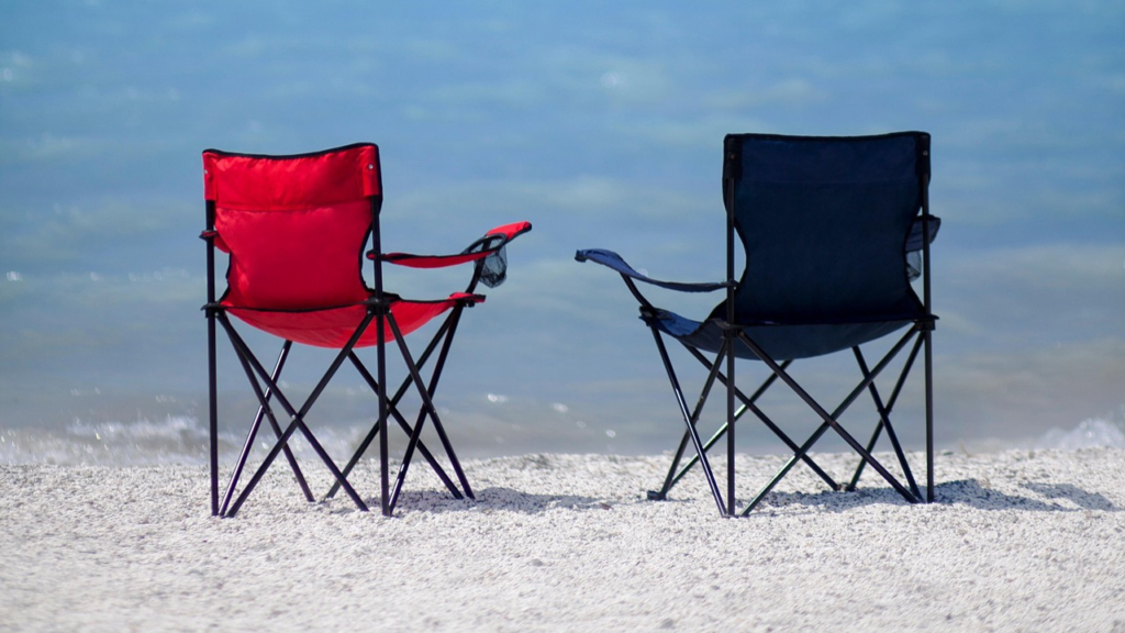 Regular standard beach chairs. One red and one black. On the beach 
