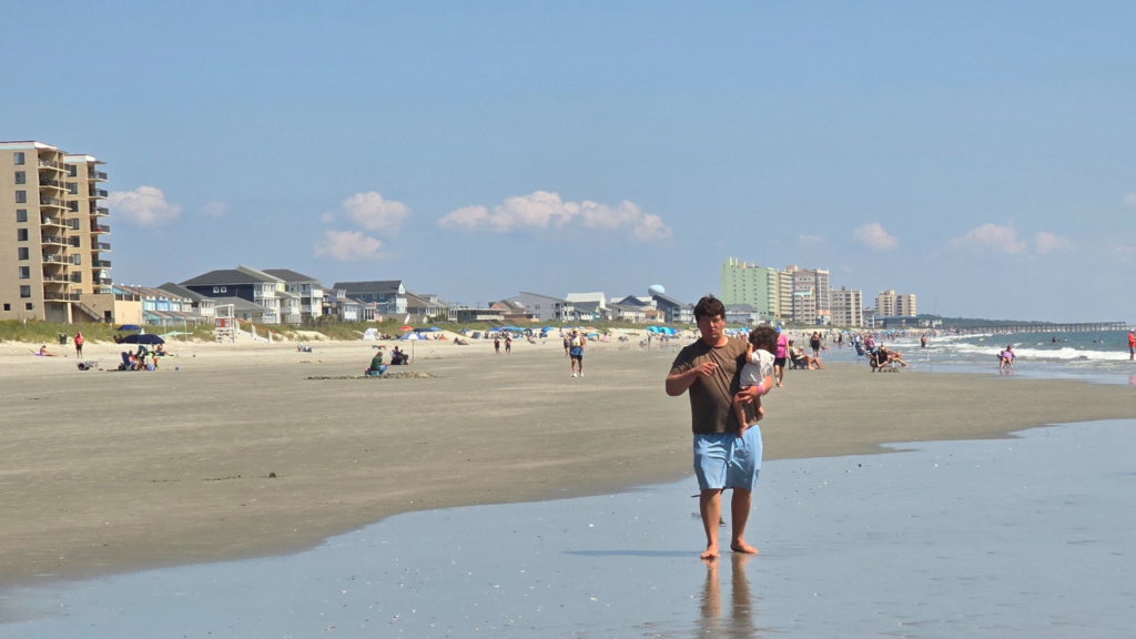 walking the shoreline observing patterns in the sand with toddler girl
