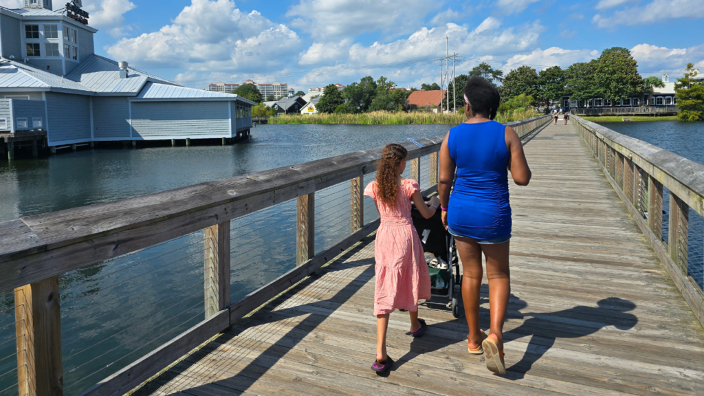 Biracial daughter and black mom walking along a bridge over water