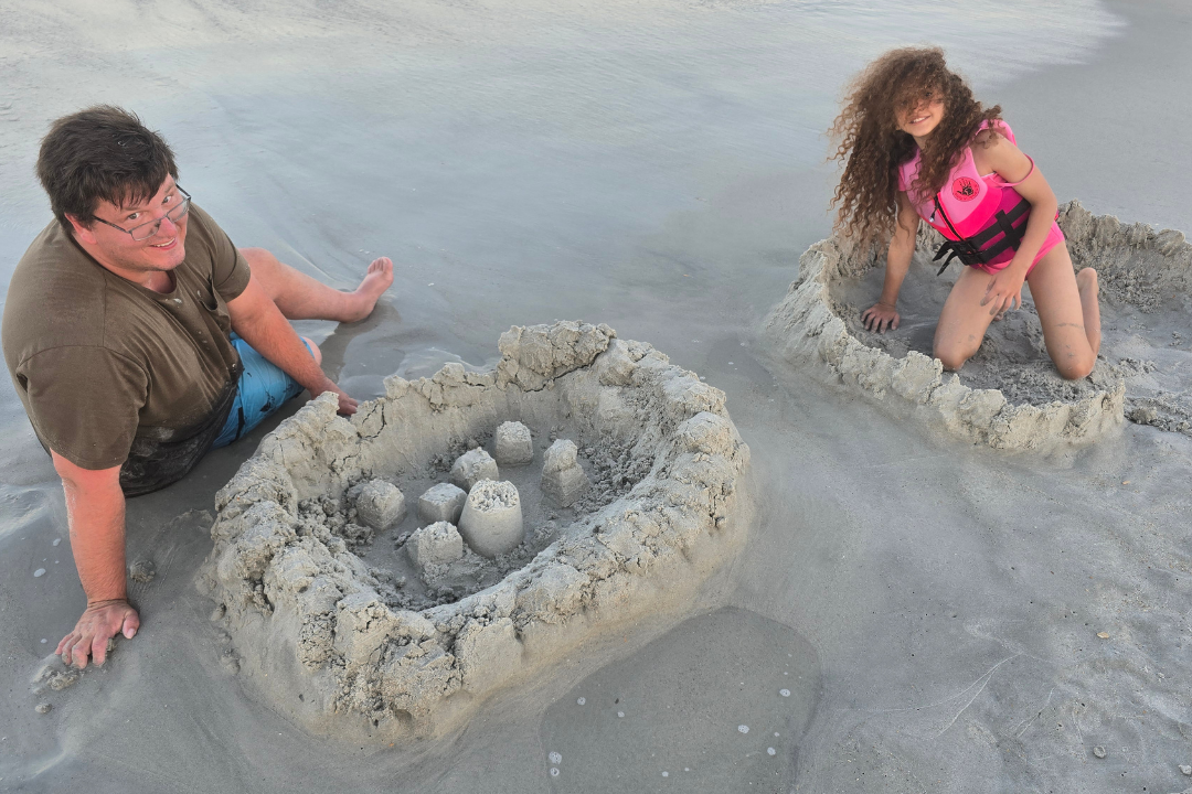 Caucasian dad and biracial daughter building sandcastles in the sand at the beach